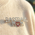 Decorative brooch with 'BASEBALL MOM' text on a beige fabric background