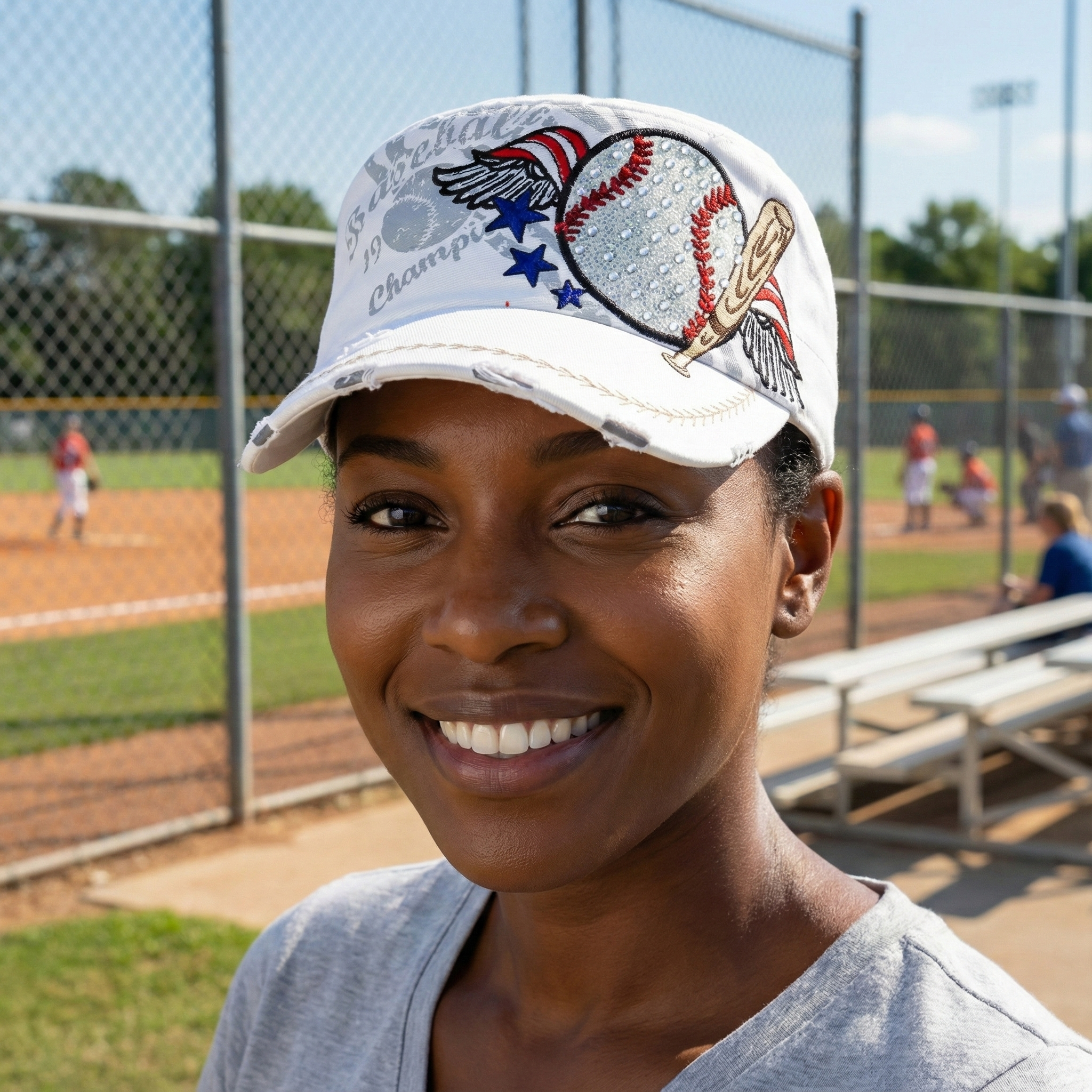 Woman wearing a baseball cap with a sports-themed design on a baseball field.
