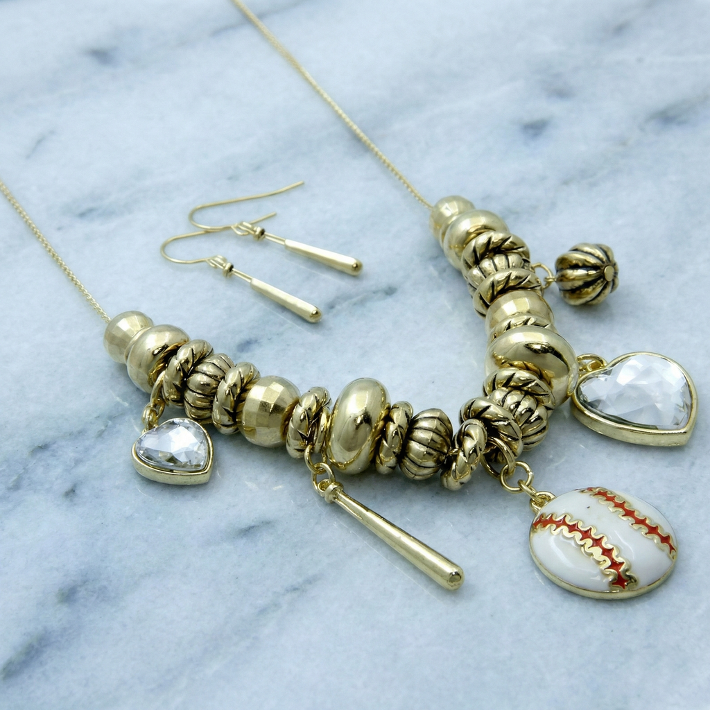 Gold necklace with heart and baseball charm on a marble background