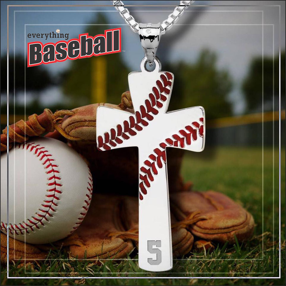 Baseball-themed cross necklace with baseball stitching design on a grassy field background.