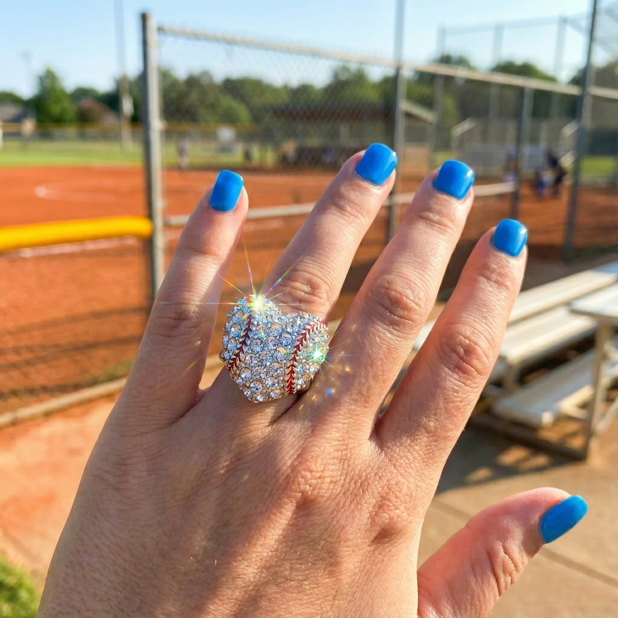Hand wearing Baseball Crystal Heart Stretchy Ring on a sports field background