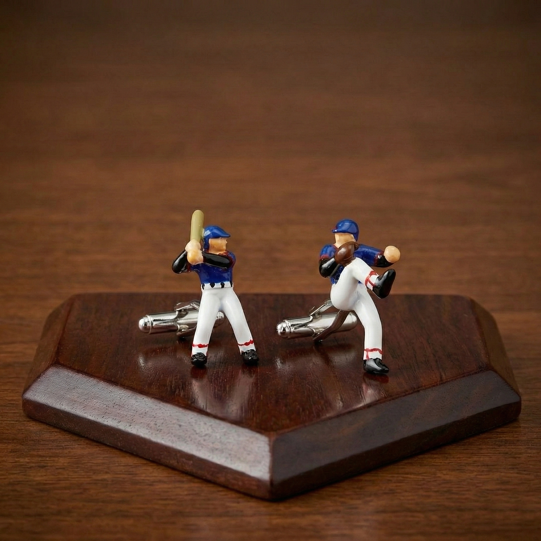 Baseball Player Cufflinks on a wooden home plate.