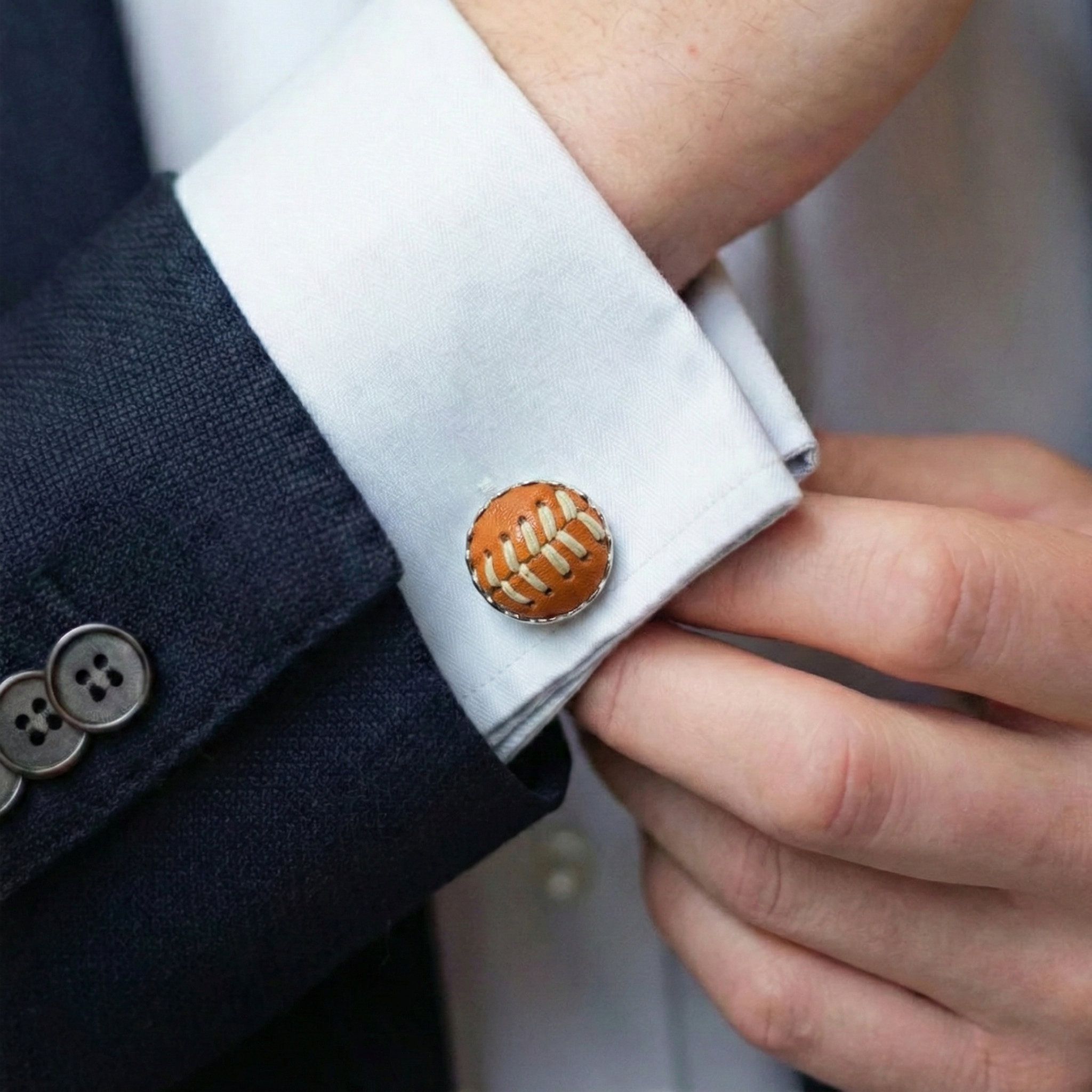 Baseball cufflink on a white cuff with navy suit and white shirt