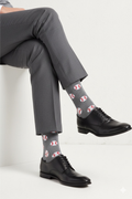 Person wearing gray dress pants and black shoes with patterned gray socks on a white background