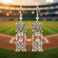 Earrings with 'MOM' letters and baseball design on a blurred baseball field background