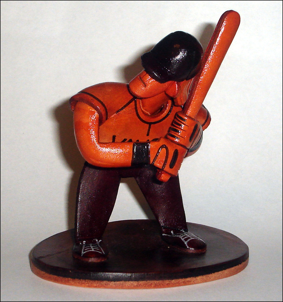 Small figurine of a baseball player holding a bat on a white background
