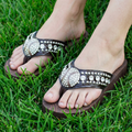 Brown sandals with baseball rhinestone embellishments on grass