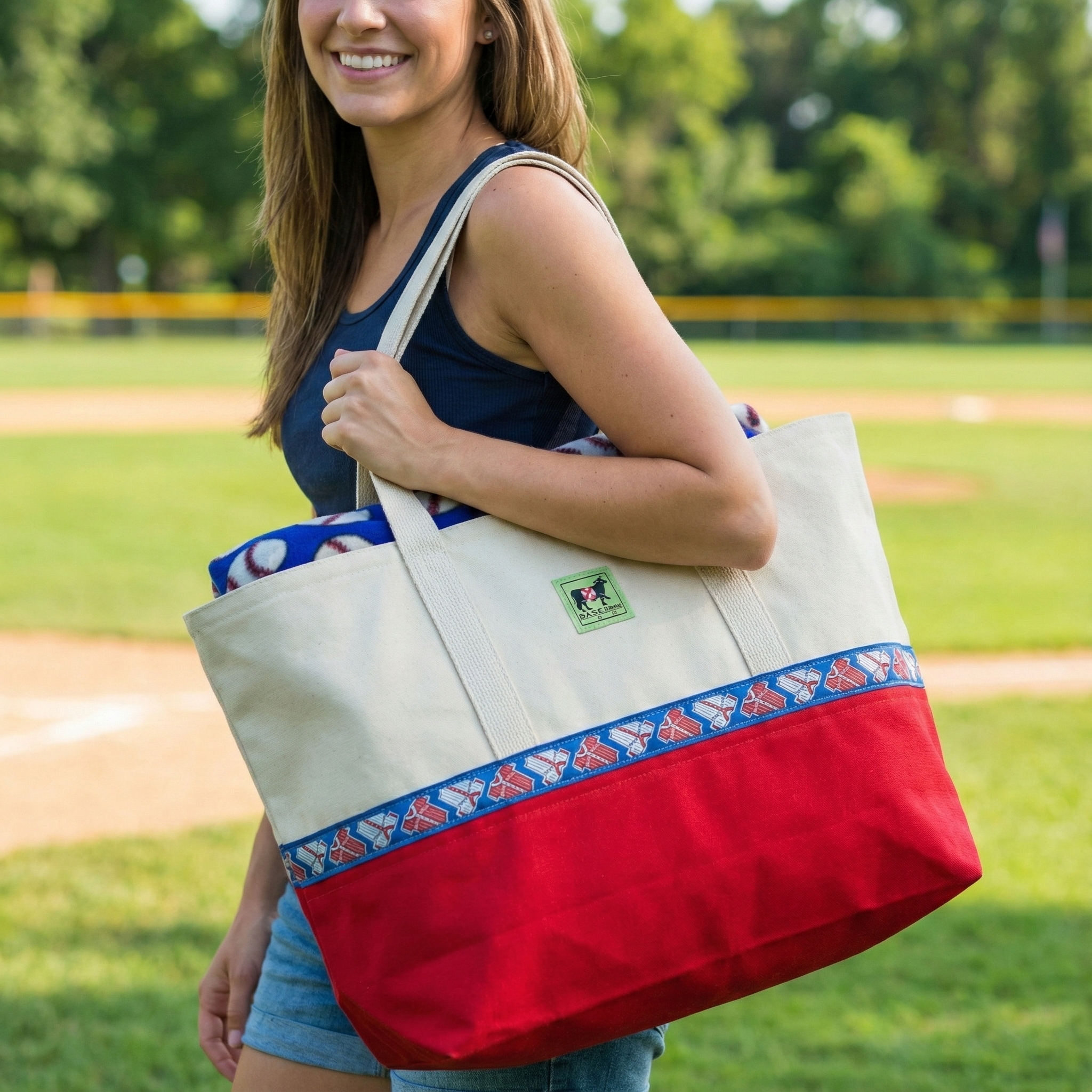 Woman holding a large baseball tote bag with a colorful band on a grassy field