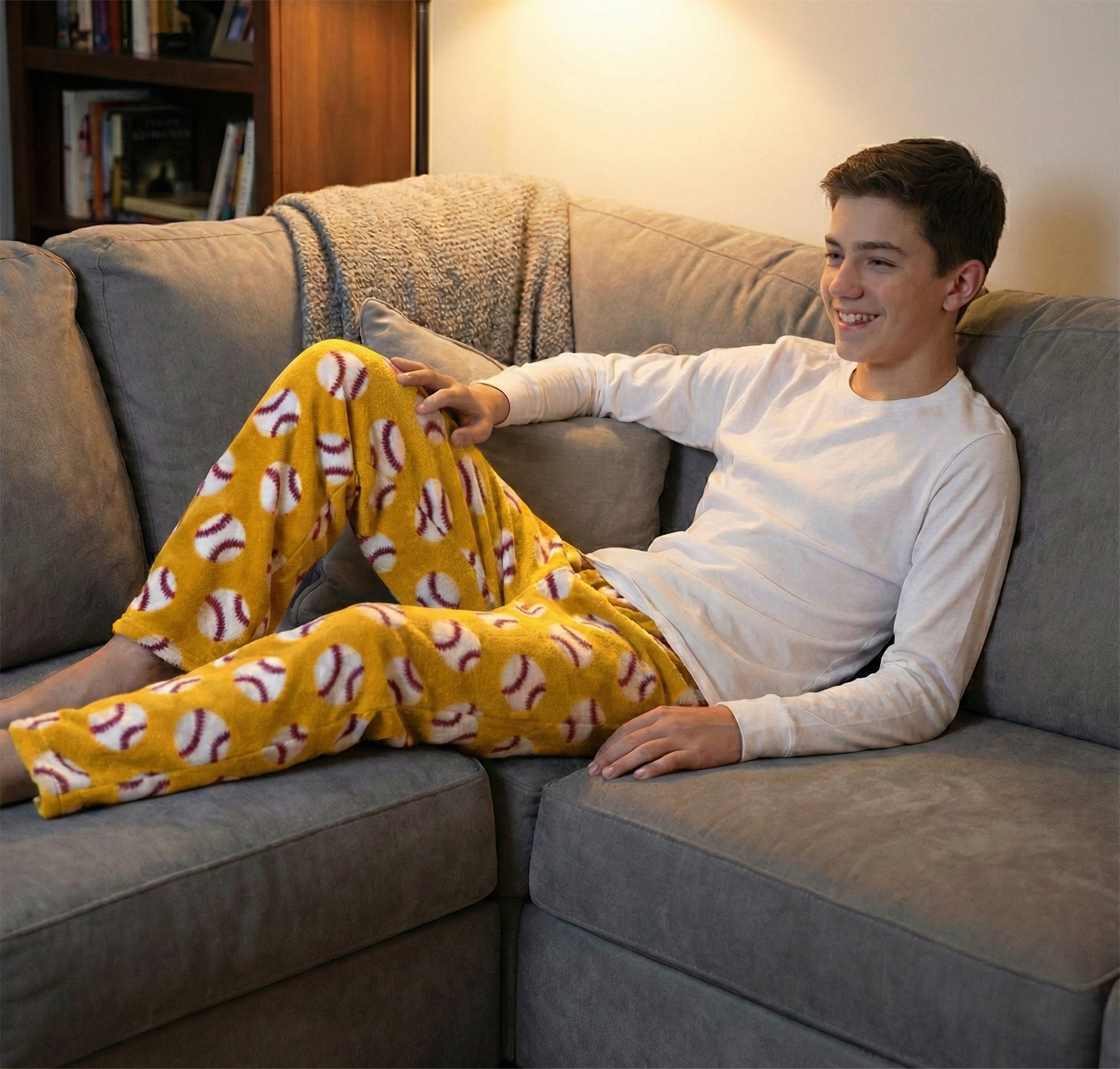 Person wearing yellow pajama pants with a pattern sitting on a gray couch.