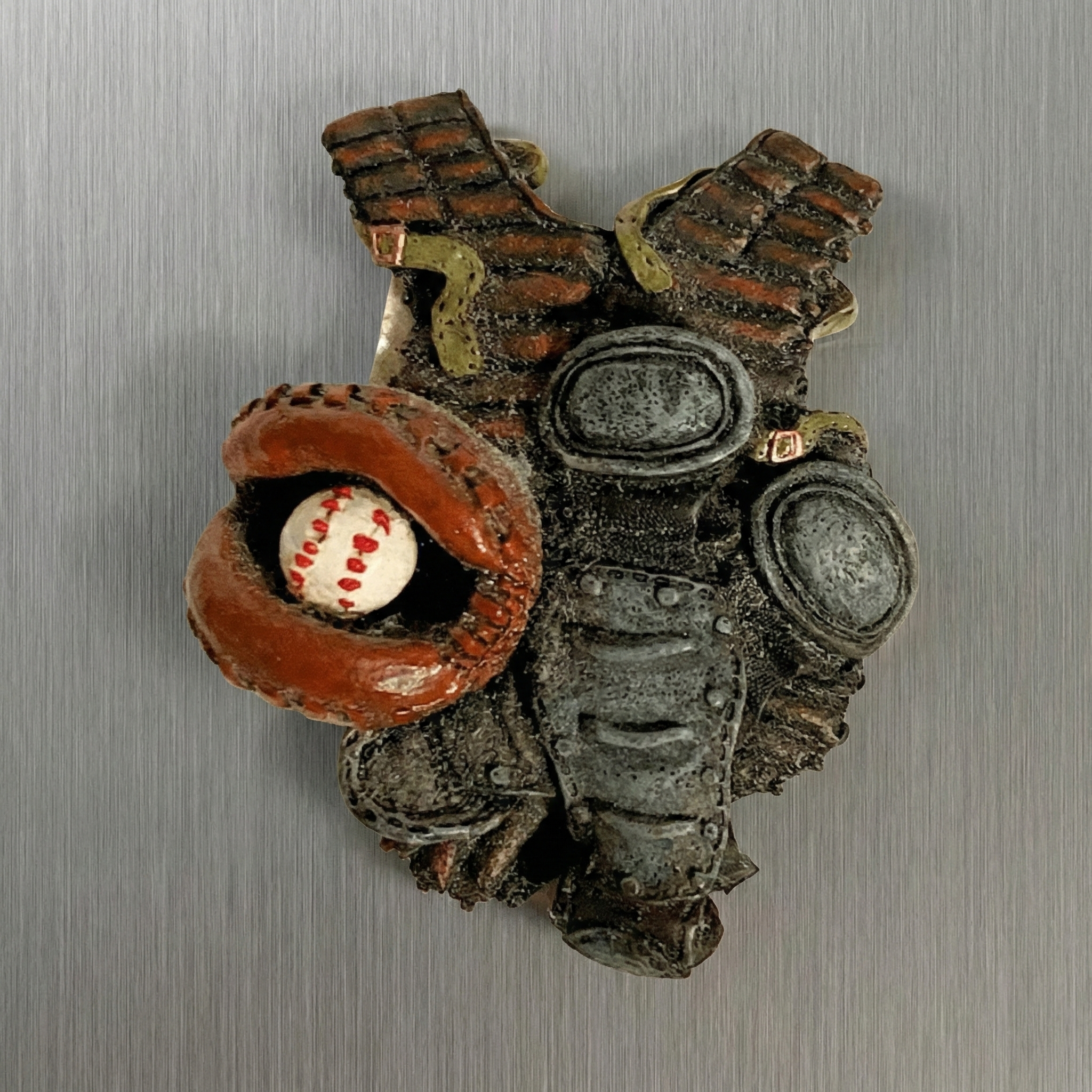 Decorative baseball catcher magnet with a baseball glove, ball, and mechanical design on a metallic background