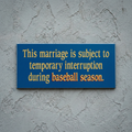 Baseball marriage blue sign with yellow text on a gray wall