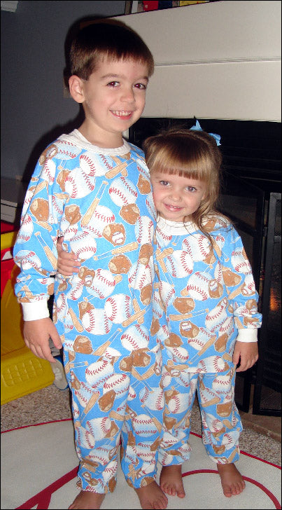 baseball pajamas worn by brother and sister by a fireplace. 