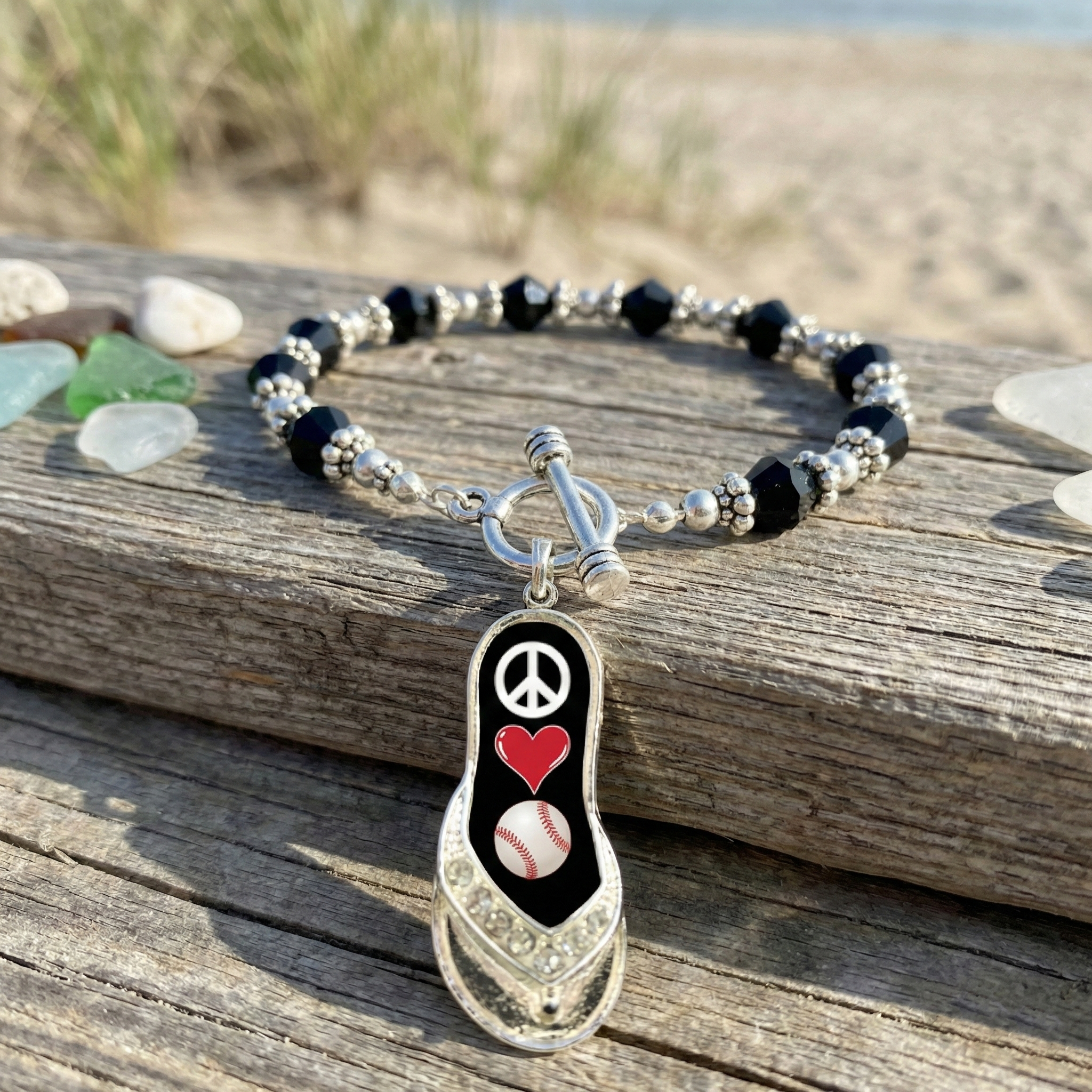 peace love baseball flip flop toggle bracelet near the beach displayed on wood with colorful sea glass. 