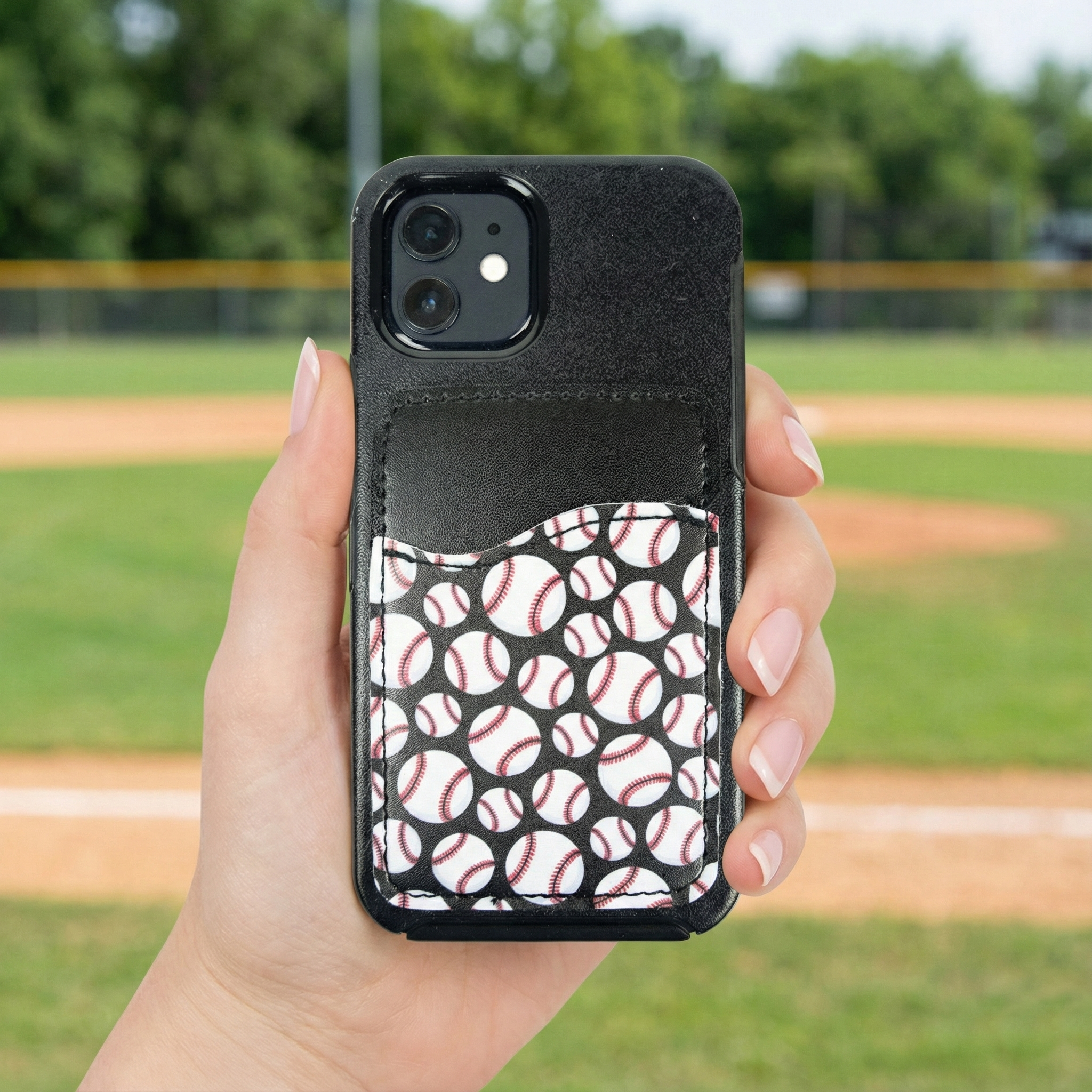 Phone case with baseball pattern cell phone pocket held by a hand on a baseball field background