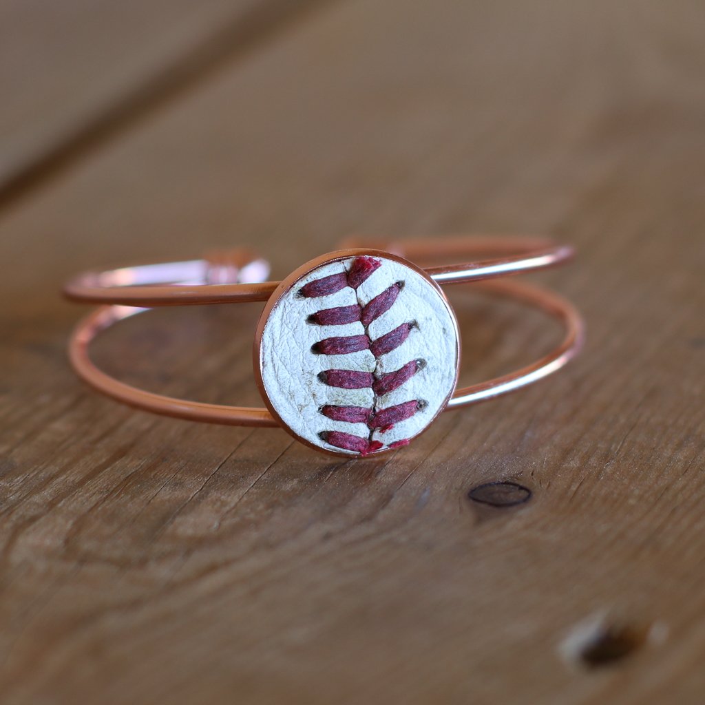 Rose gold bracelet with a baseball design on a wooden surface