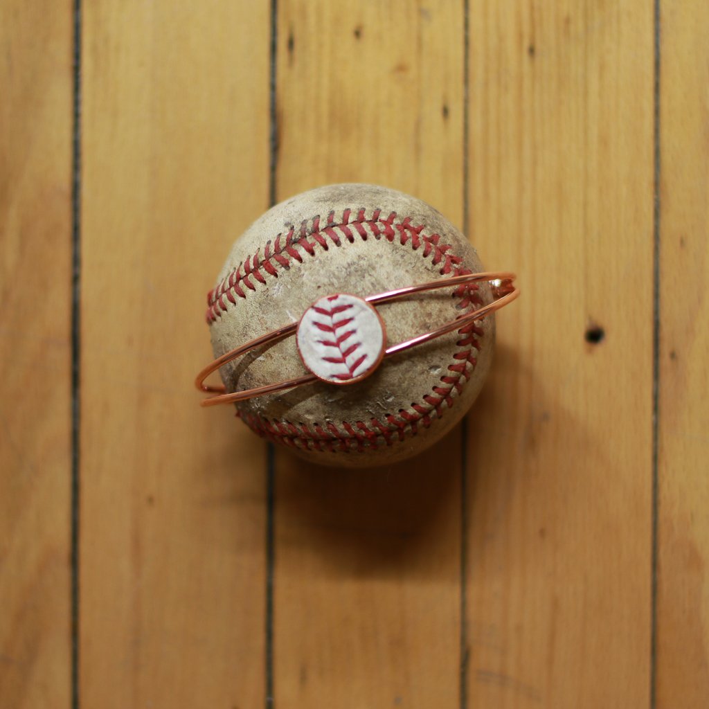 Worn baseball with a bracelet on a wooden surface