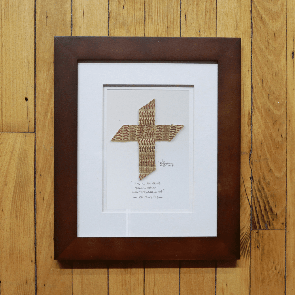 Framed cross made of baseball seams on a wooden surface