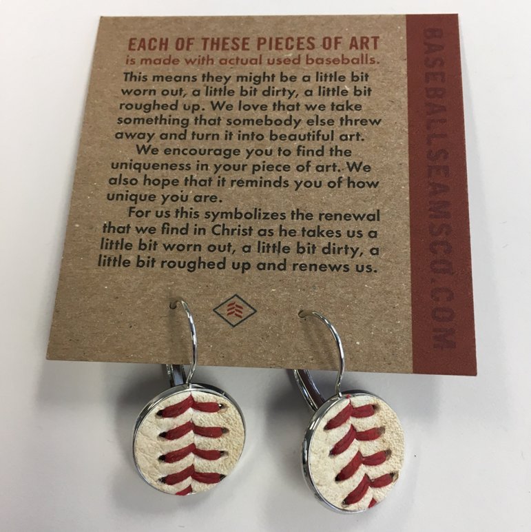 Baseball seam earrings on a card with text about their creation process.