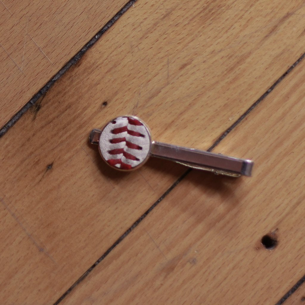 Baseball-shaped tie clip on a wooden surface