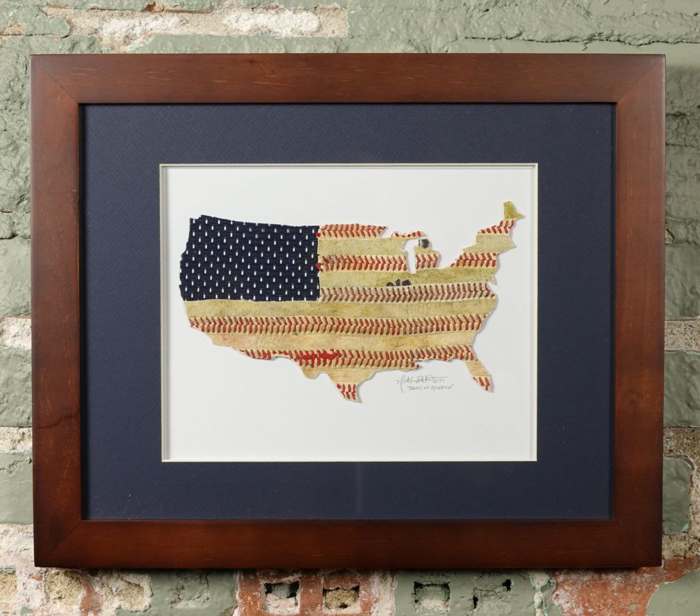 Framed artwork of a baseball seams map of the United States with American flag patterns on a brick wall background.