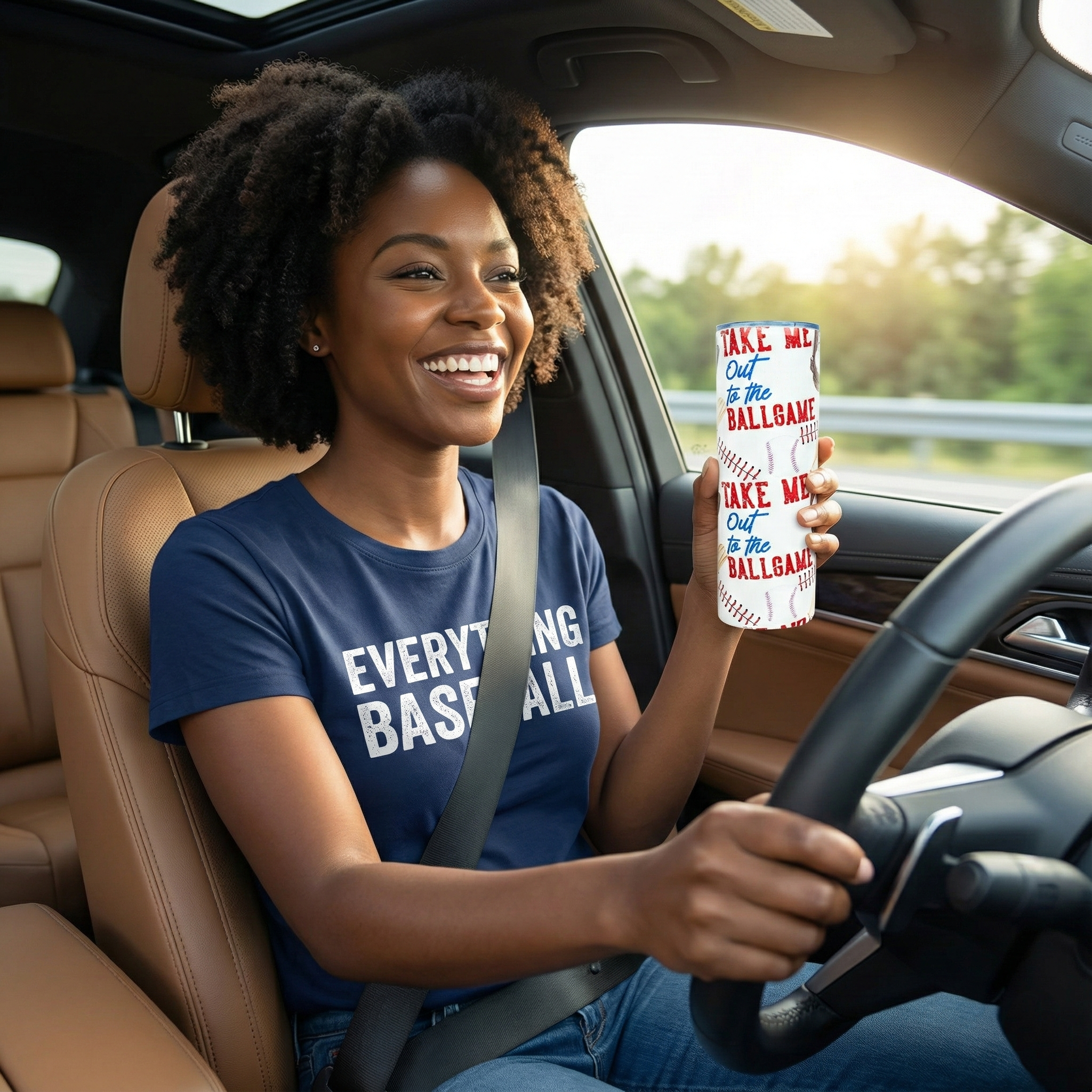 Woman driving a car holding a baseball travel mug with text, smiling.