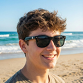 Person wearing baseball sunglasses on a beach with ocean in the background