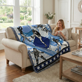 Woman sitting on a couch with a blue and black baseball patterned blanket, holding a mug.
