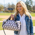 Woman holding a baseball patterned handbag outdoors on a sunny day