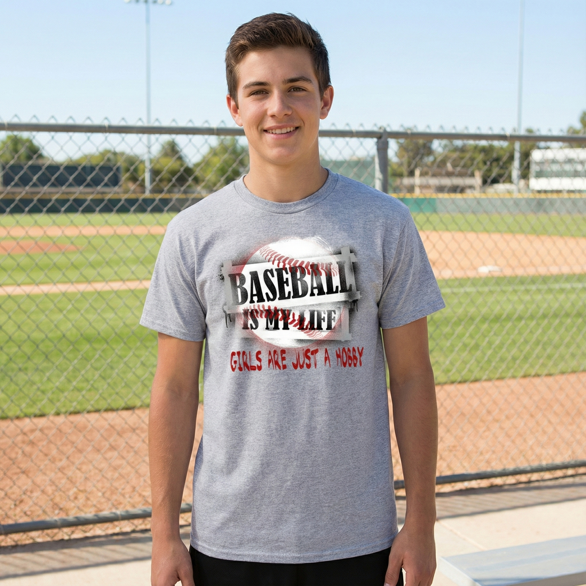 Person wearing a gray t-shirt with a baseball-themed design on a baseball field.