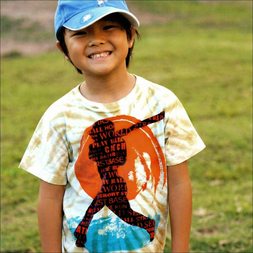 Child wearing a t-shirt with a baseball graphic design outdoors