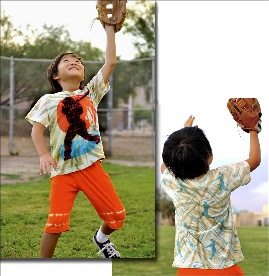 Child in a tie-dye shirt and orange shorts catching a baseball with a baseball glove.