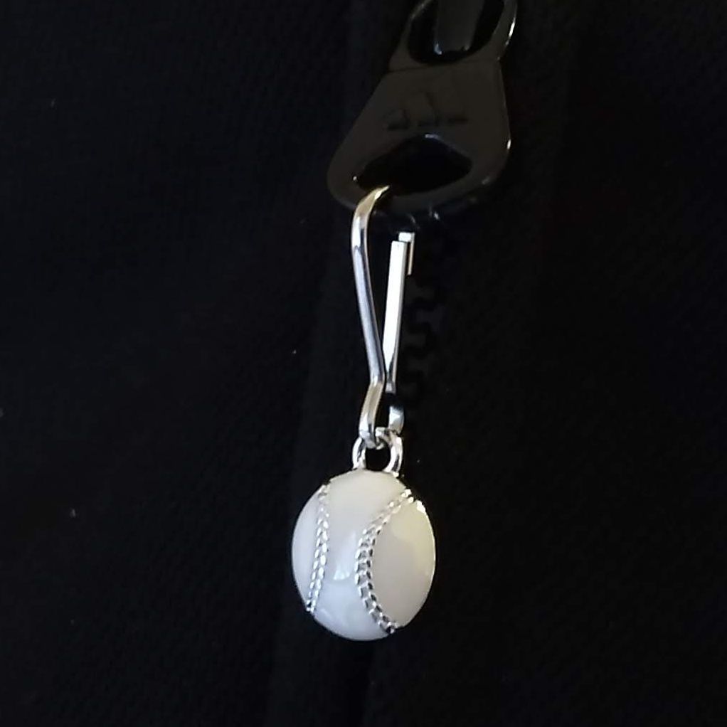 Baseball-shaped zipper pull on a black background