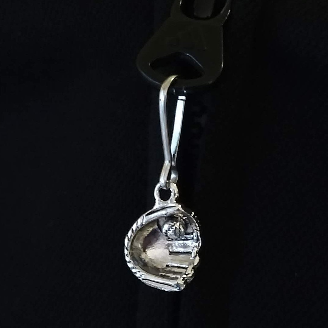 Silver baseball in glove zipper pull on a black background