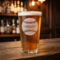 Glass of cold beer with an etched baseball on a wooden bar counter