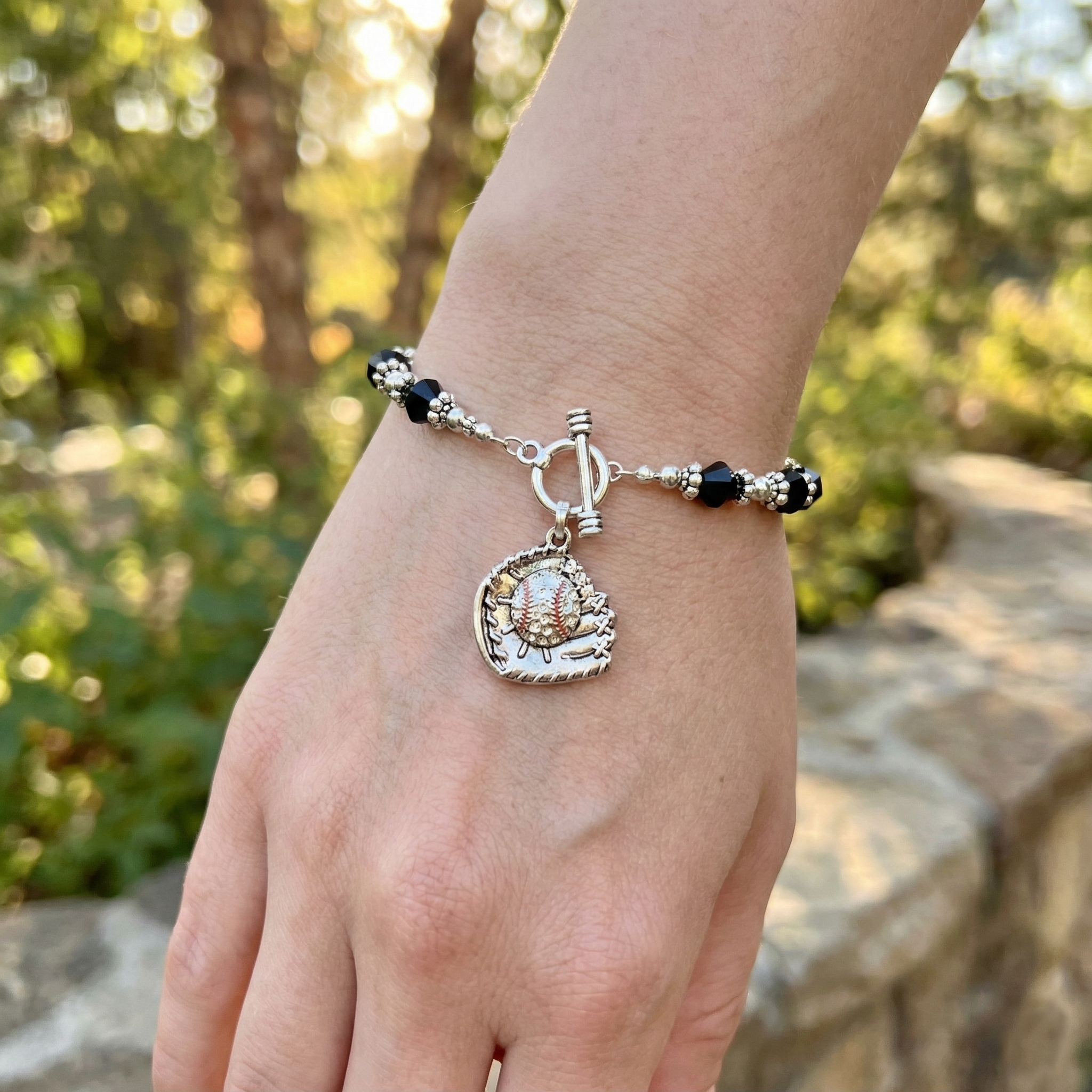 Bracelet with a baseball charm on a wrist against a natural background