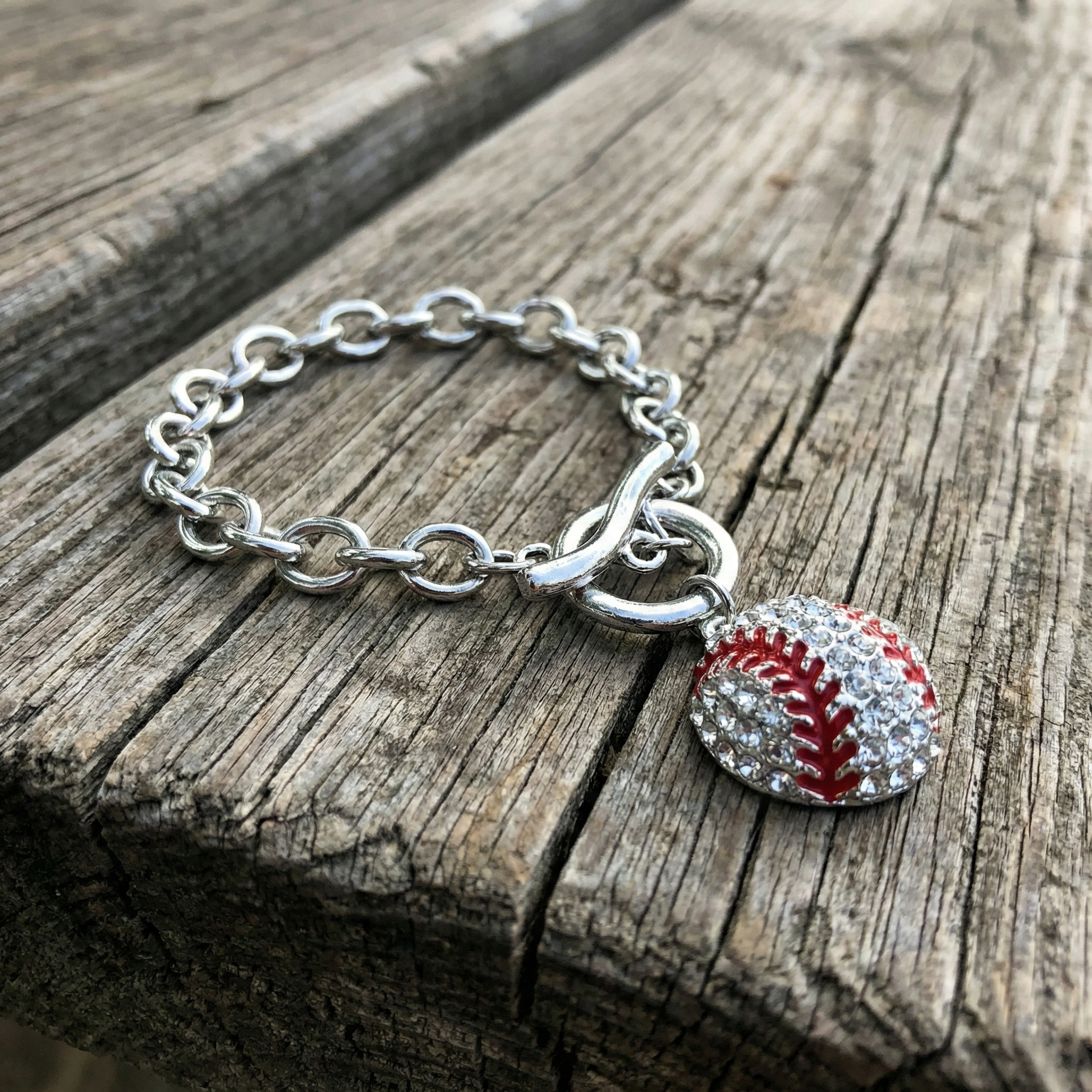 Bracelet with a baseball charm on a wooden surface