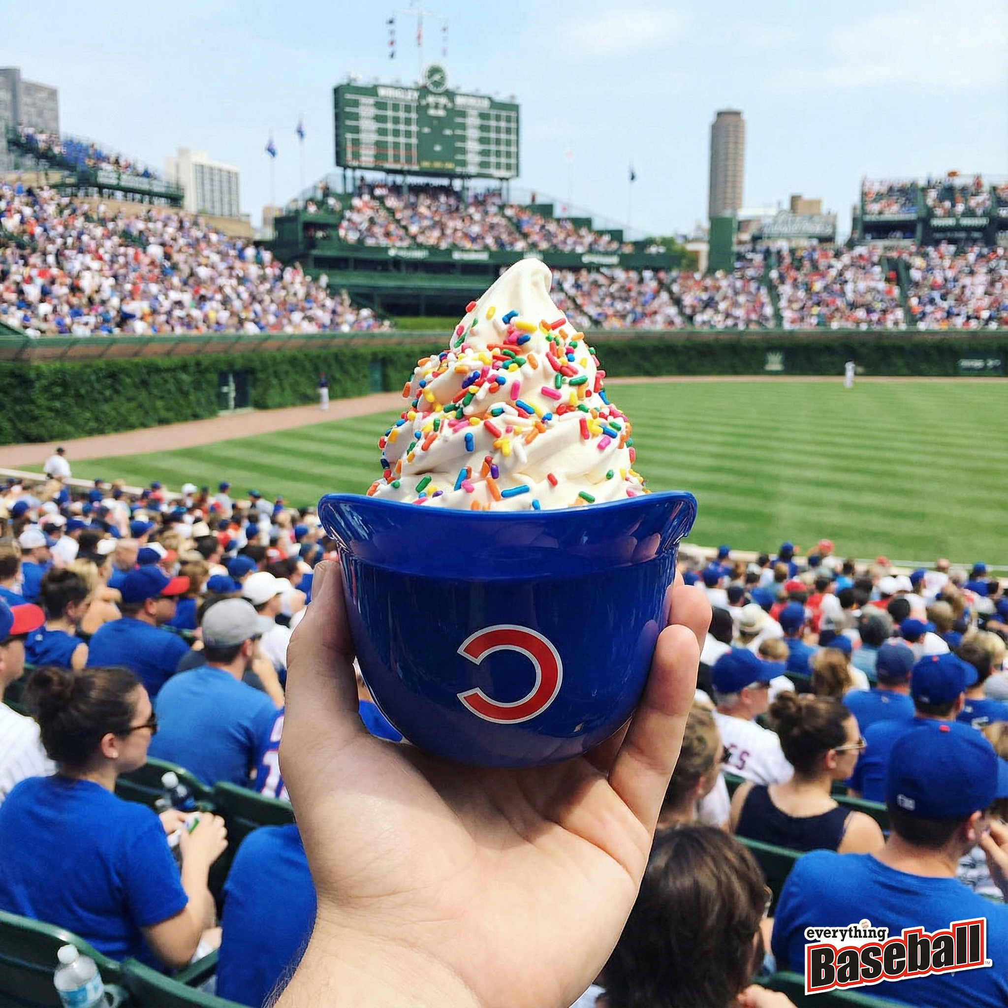 Hand holding a blue Chicago Cubs helmet bowl with ice cream at a baseball game at Wrigley Field