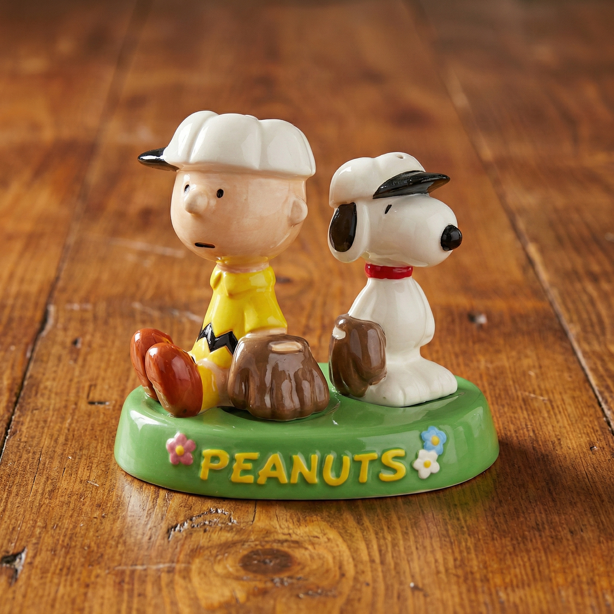 Salt Pepper Shaker Set of Charlie Brown and Snoopy Baseball Players with a 'Peanuts' base on a wooden surface