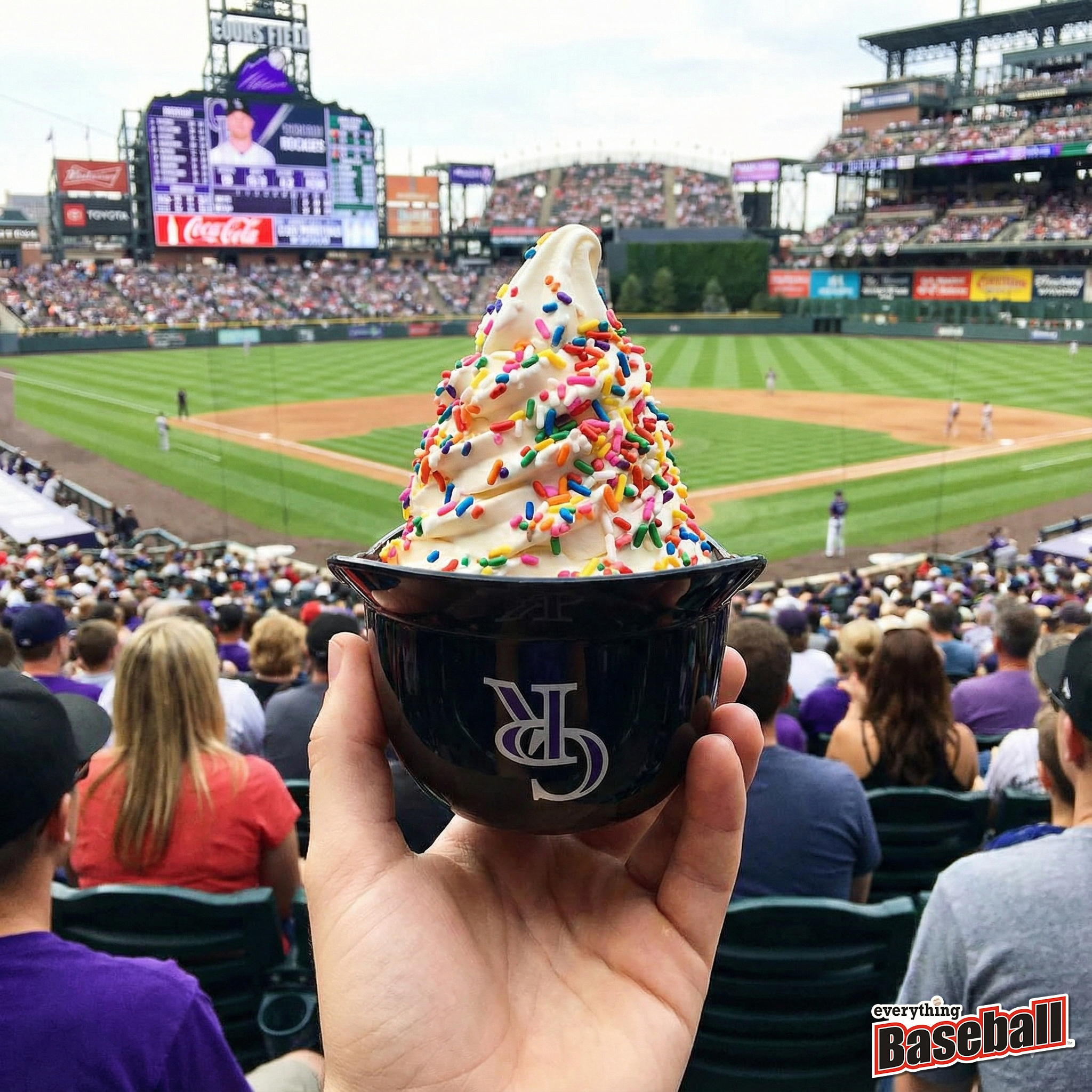 Colorado Rockies helmet ice cream sundae with colorful sprinkles held up at a baseball game