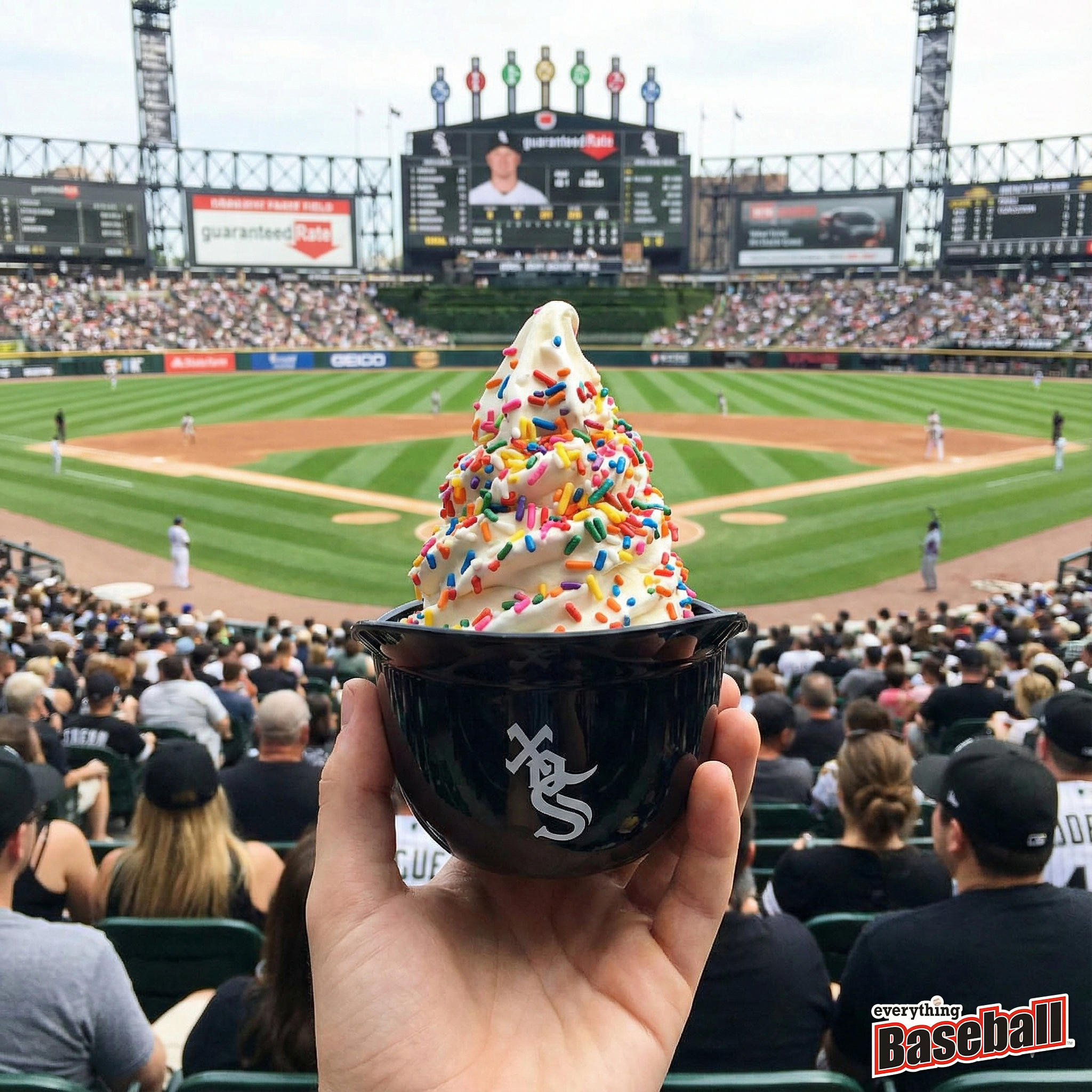 Hand holding a Chicago White Sox helmet bowl of ice cream with colorful sprinkles at a baseball game.