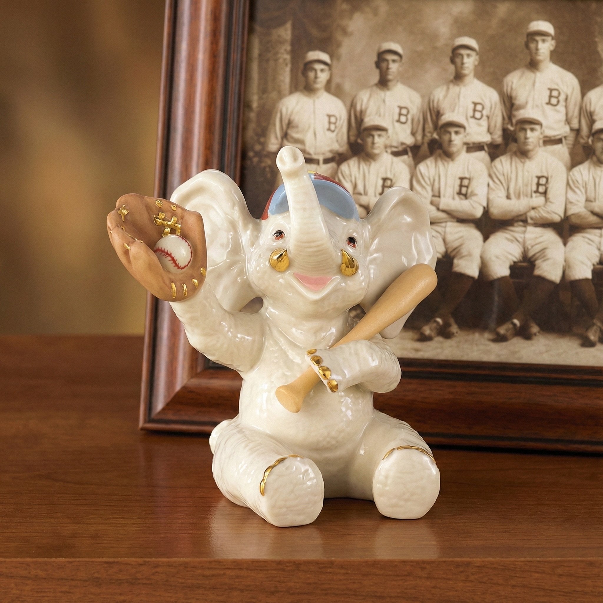 Decorative elephant figurine holding a baseball bat in front of a framed photo of a vintage baseball team.
