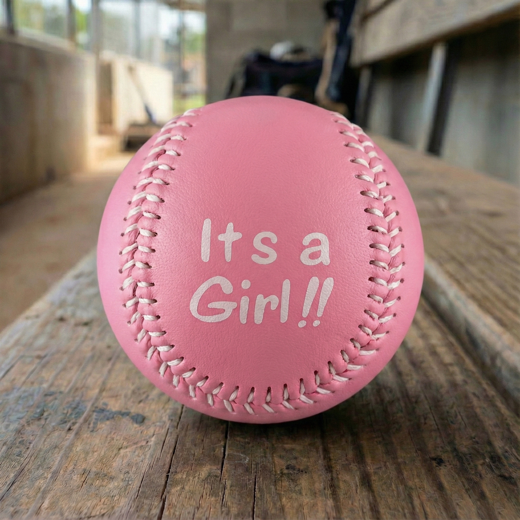 Pink baby baseball with 'It's a Girl!!' text on a wooden dugout bench