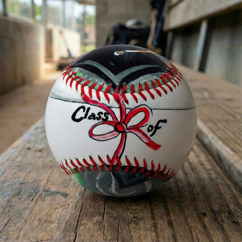 Graduation baseball with 'Class of' and bow design on a wooden dugout bench