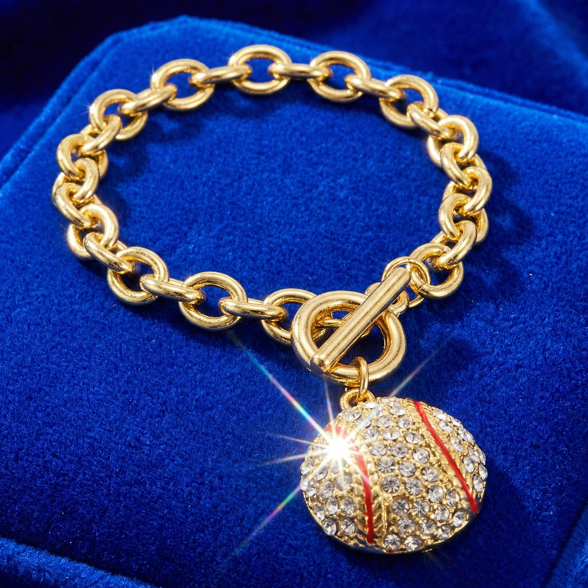 Gold chain bracelet with a baseball charm on a blue velvet background
