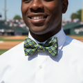 Man wearing a white shirt and baseball field patterned bow tie on a sports field