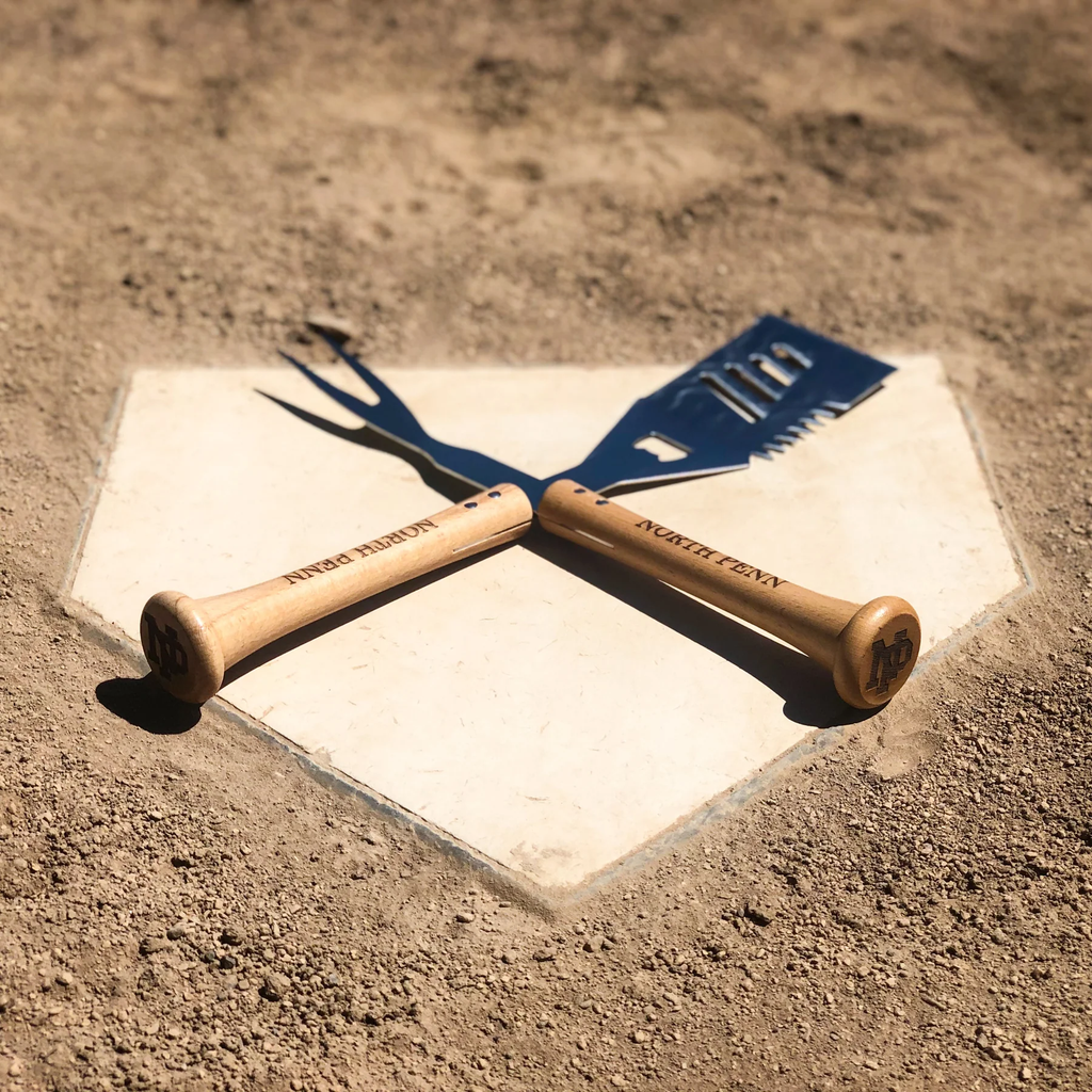 Baseball bat grill tools on a home plate with 'North Penn' branding.