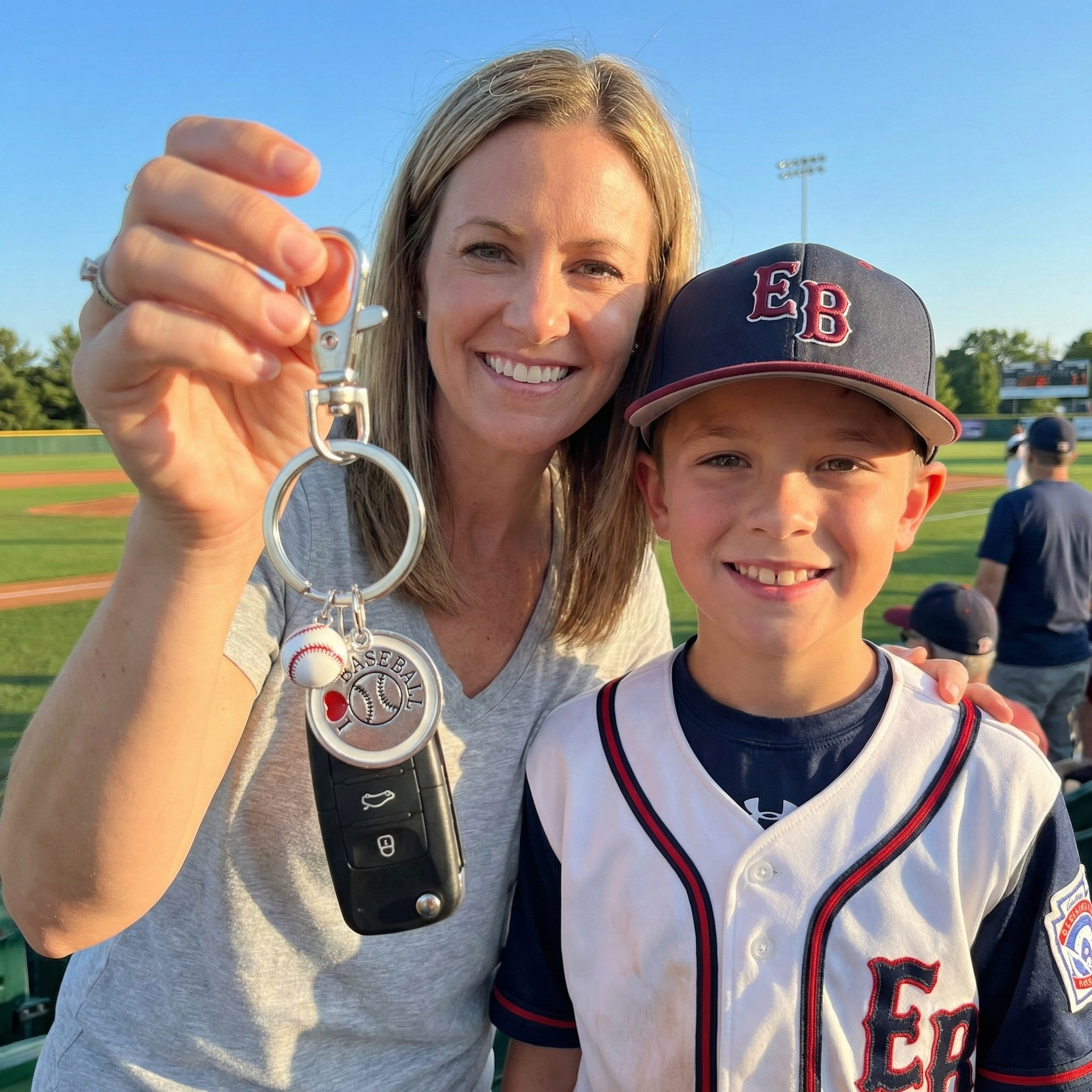 Woman and young boy on a baseball field holding an I love baseball keychain