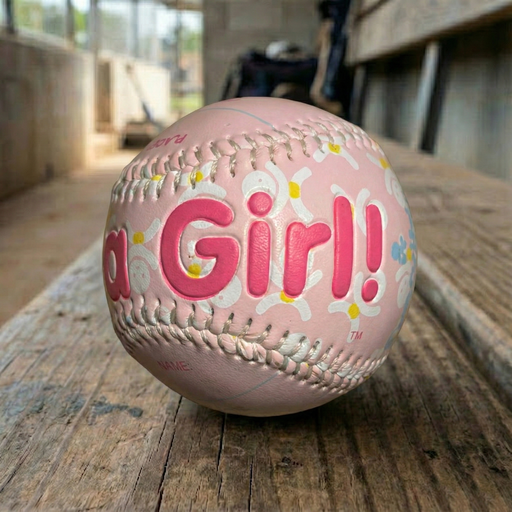 It's a Girl Pink Baby Baseball Keepsake in a dugout by the field