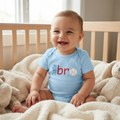 Little Bro Baseball Onesie on a baby sitting in a crib