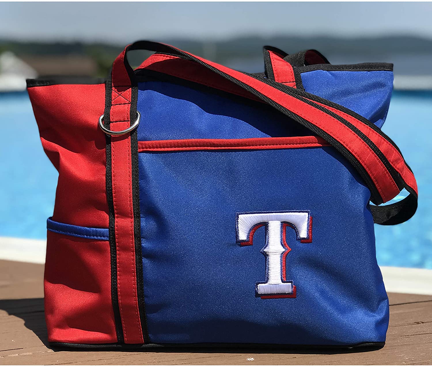 Texas Rangers tote bag with a logo on a wooden surface by a body of water.